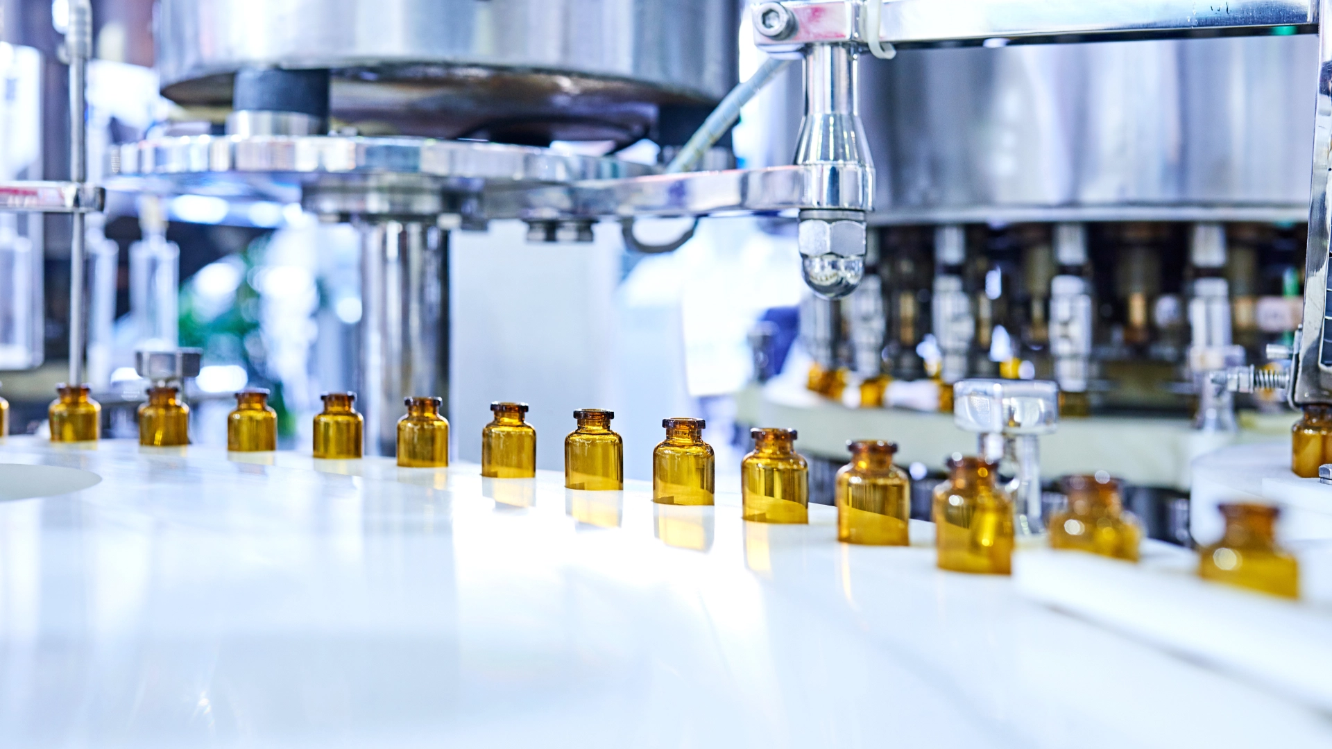 Automated pharmaceutical production line filling glass vials in a sterile manufacturing facility.